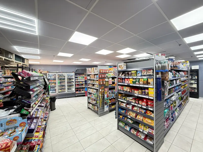 A wide view of the shop floor with aisles of snacks, sweets and groceries under bright lighting