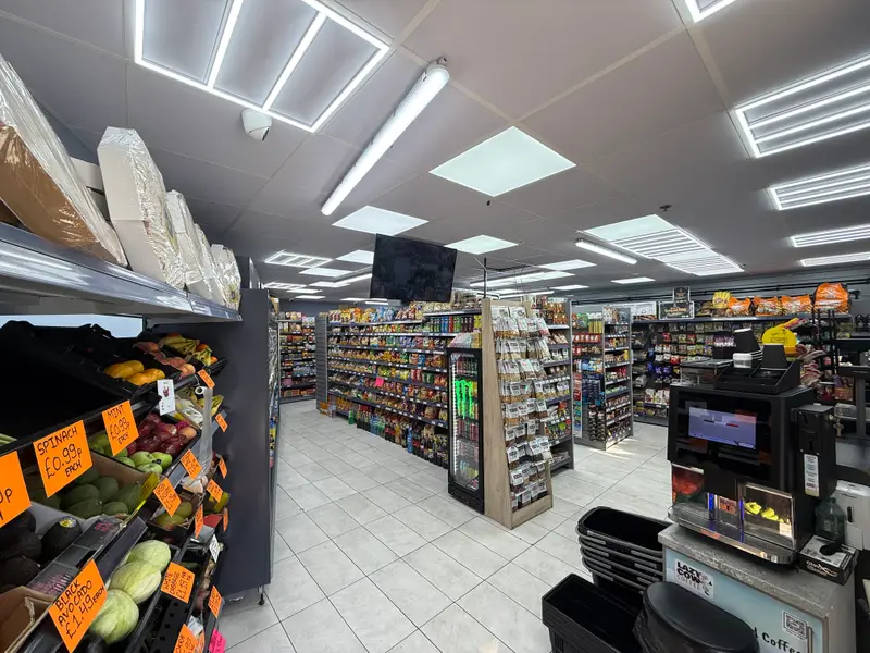 Inside the shop, with fresh fruit and vegetables on the left, bright aisles of groceries and the till area ahead